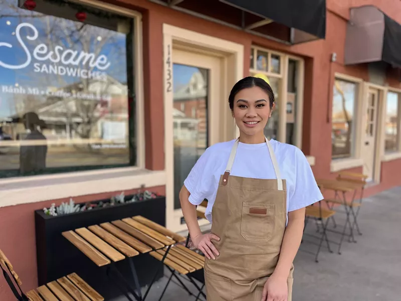 Image: woman standing in front of a storefront in an apron