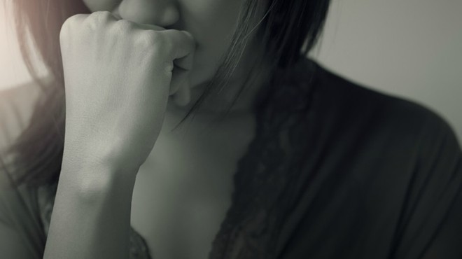 closeup of depressed girl with hand to mouth