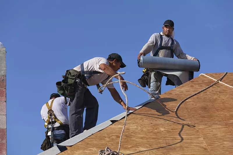 Image: three men working on roof.