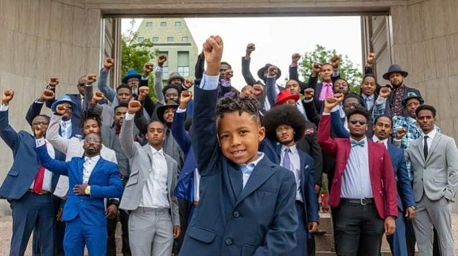 group of well-dressed black kids, hands in air.