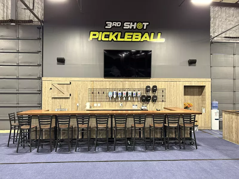 Image: stools lined up in front of a large table indoors