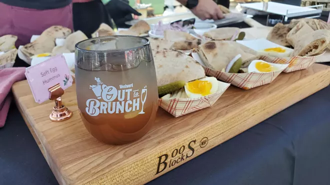 a cup on a cutting board next to samples of hummus