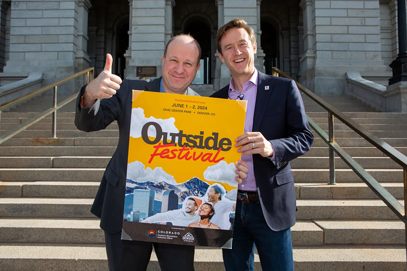 Image: two men in suits with poster