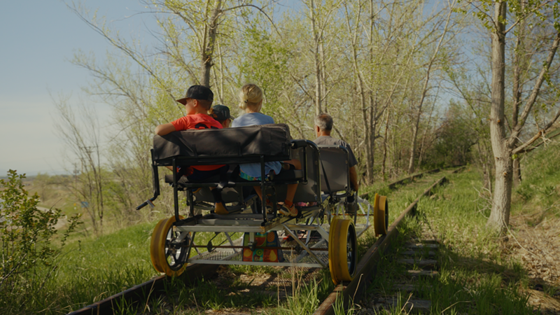 Image: A family pedaling a railbike through a forested stretch in Erie, Colorado