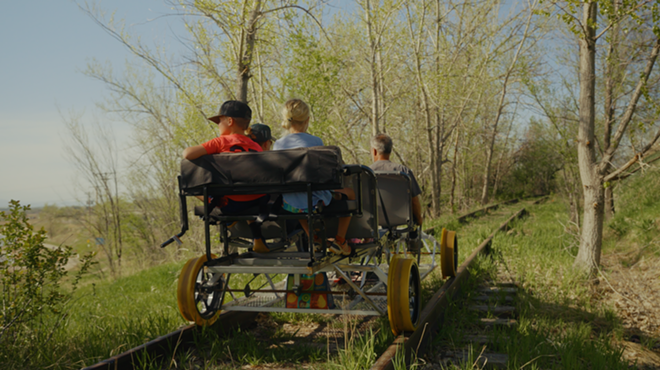 A family pedaling a railbike through a forested stretch in Erie, Colorado