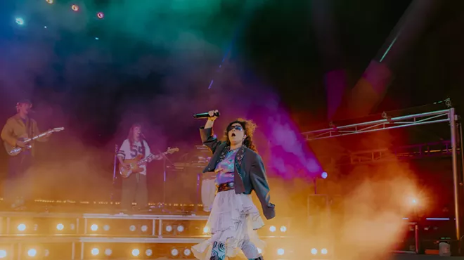 A picture of Remi Wolf performing on stage at Red Rocks with fog and stage lights behind her.