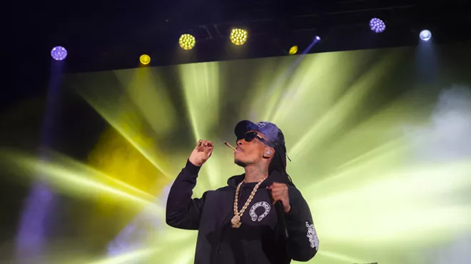 A photo of Wiz Khalifa on stage at Red Rocks smoking a joint.