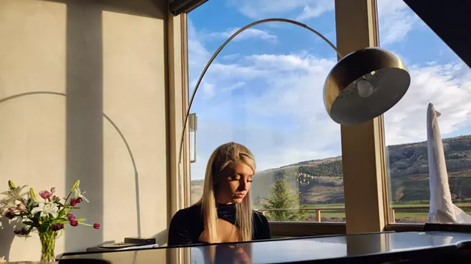 blonde woman playing a baby grand piano.