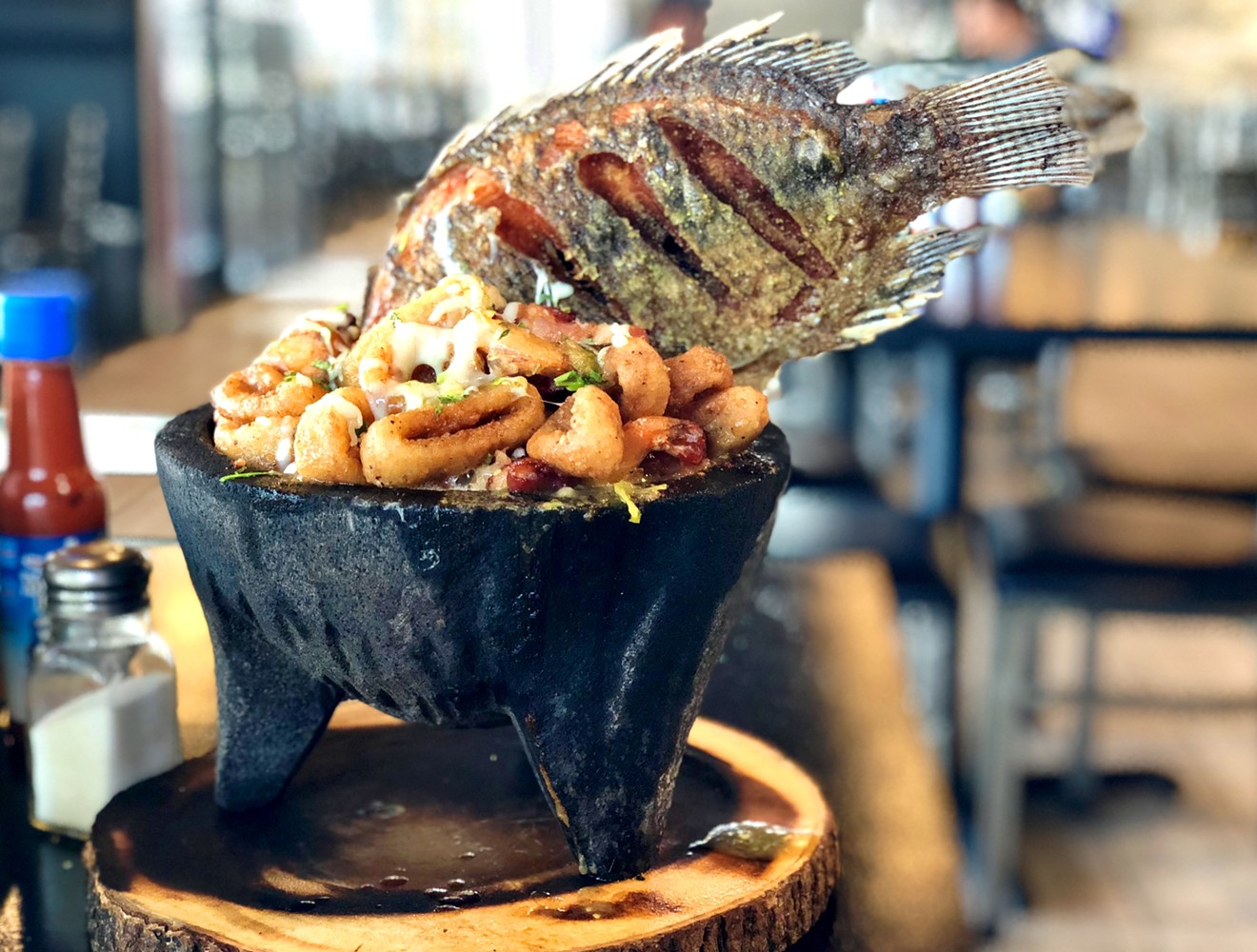A whole mojarra plunges into a sizzling seafood molcajete.