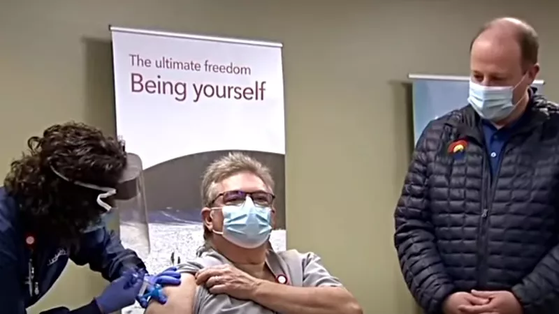 Image: Governor Jared Polis watching one of Colorado's first COVID-19 vaccinations on December 14.