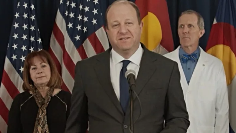 Image: Governor Jared Polis, flanked by Dianne Primavera and Dr. Eric France, during a February 25 press conference about COVID-19.