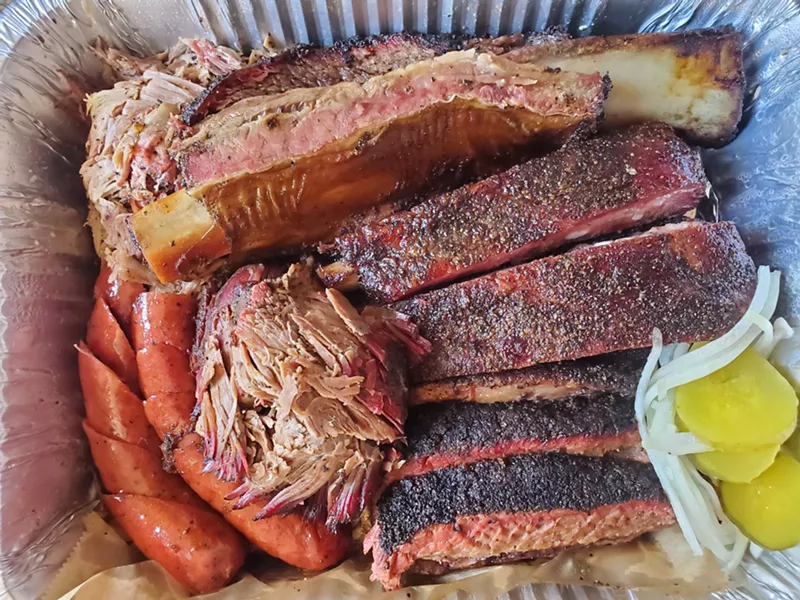 Image: a pan of barbecue ribs, sausages, pulled pork and brisket