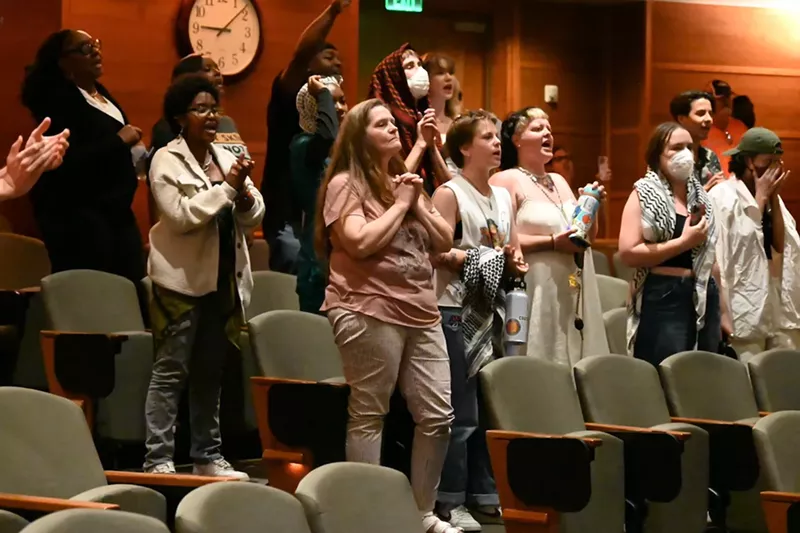 Image: Protesters chant in the city council chambers.