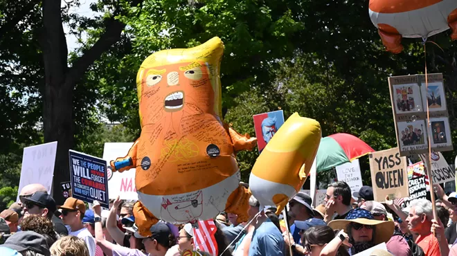 woman holds orange trump baby balloon at protest