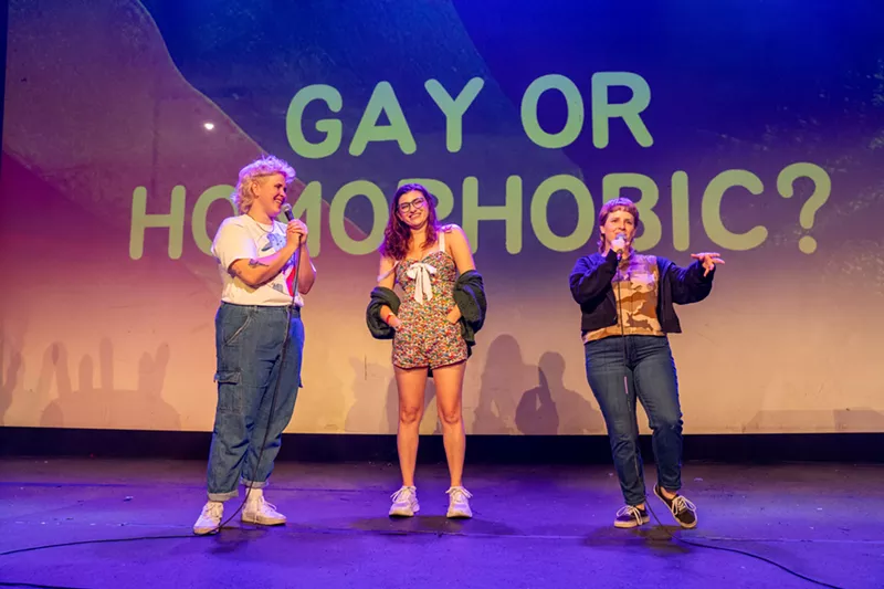 Image: women on stage in front of sign that says gay or homophobic