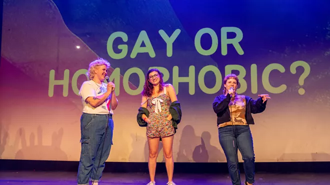 women on stage in front of sign that says gay or homophobic