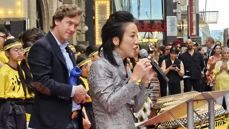 Image: woman talking into mic in front of man