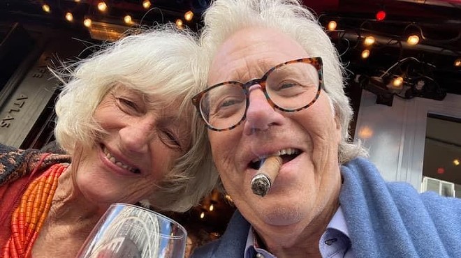 a woman next to a man smoking a cigar
