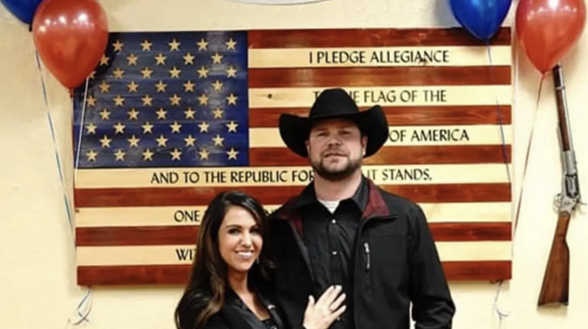 woman and man in cowboy hat in front of flag.
