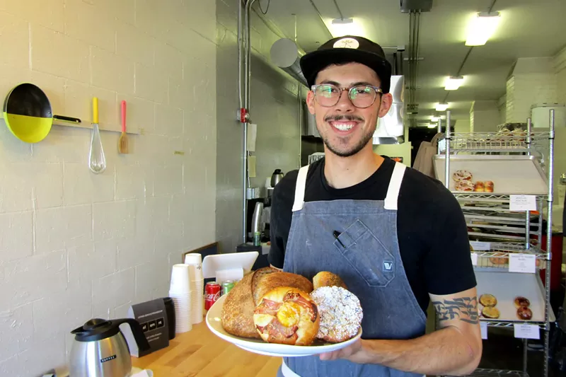 Image: Zach Martinucci shows off some of his baked goods at the new Rebel Bread.