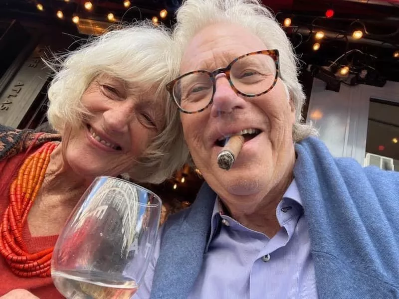 Image: a woman next to a man smoking a cigar