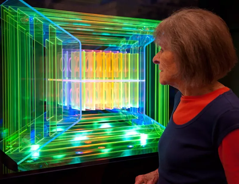 Image: Dorothy Tanner poses with her Lumonics sculpture "Logo."
