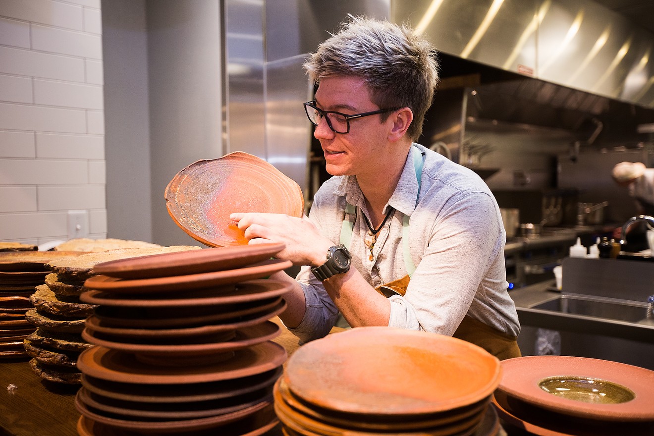 Chef Matthew Lackey points out the unique patterns of the handmade serviceware that was part of Arcana's opening.