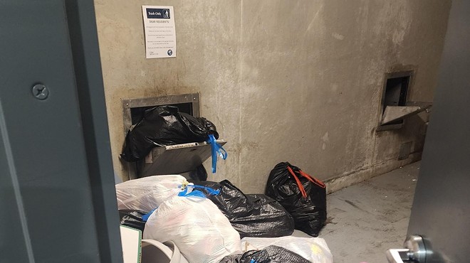 Trash bags overflow out of a garbage chute