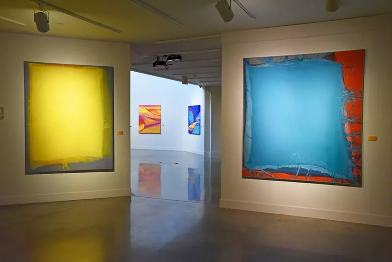Image: “Tao of Yellow” (left foreground) and “Aquamarine” (right foreground), by Virginia Maitland, poured acrylic on canvas.