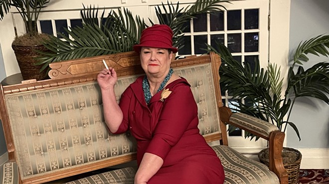 woma in maroon dress and hat on sofa