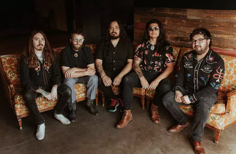 Image: bandmembers sit in a sem-circle