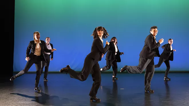 A group of people tap dance onstage.