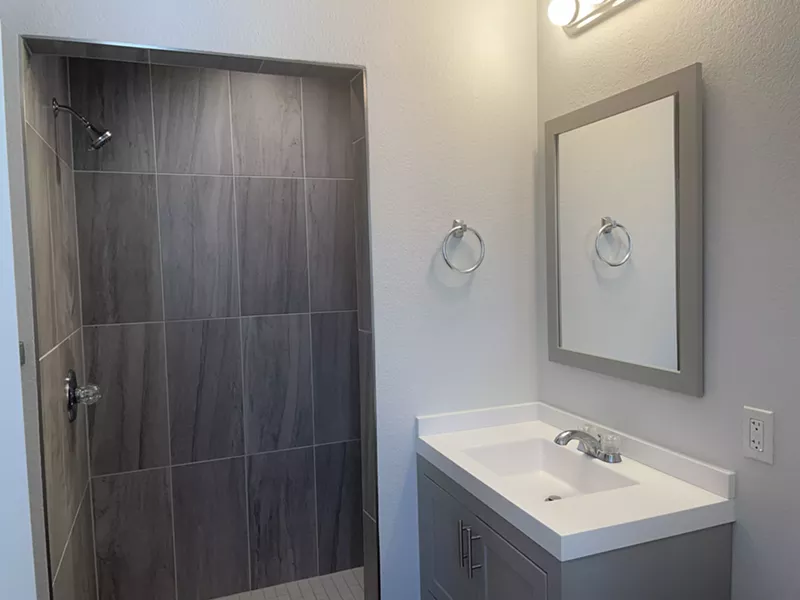 Image: A walk-in shower and sink.