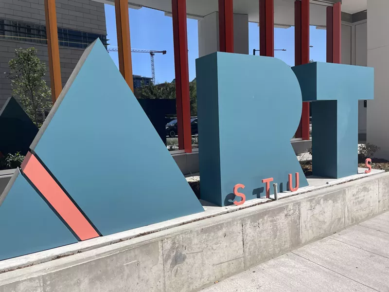 Image: A huge, teal A-R-T sign in front of an orange-columned building.