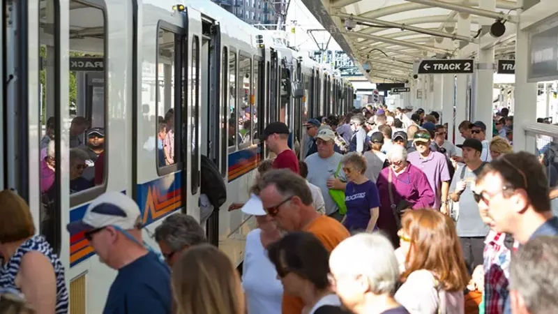 Image: People line up to get on a train.