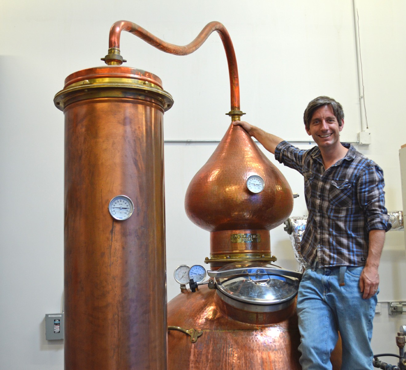 Ryan Max Riley with a copper pot still at his Ski Bum Rum distillery.