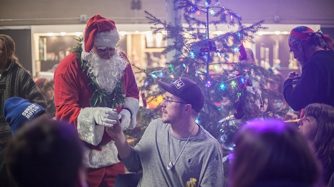 Santa Clause gifting marijuana in front of a Christmas tree
