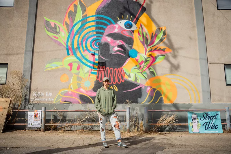 Image: person standing in front of colorful mural outside