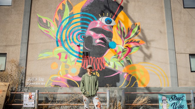 person standing in front of colorful mural outside