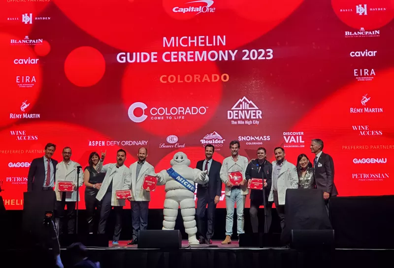 Image: people standing on a stage in front of a red background