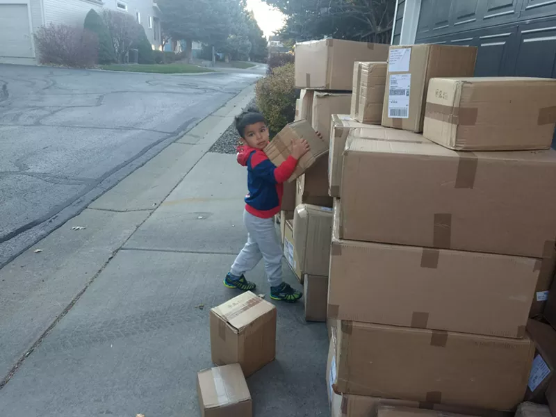Image: Erin Persaud's son helps with boxes of supplies while volunteering with I Support the Girls.