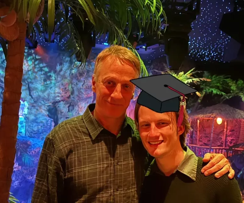 Image: graduation cap graphic on a man posing with his father