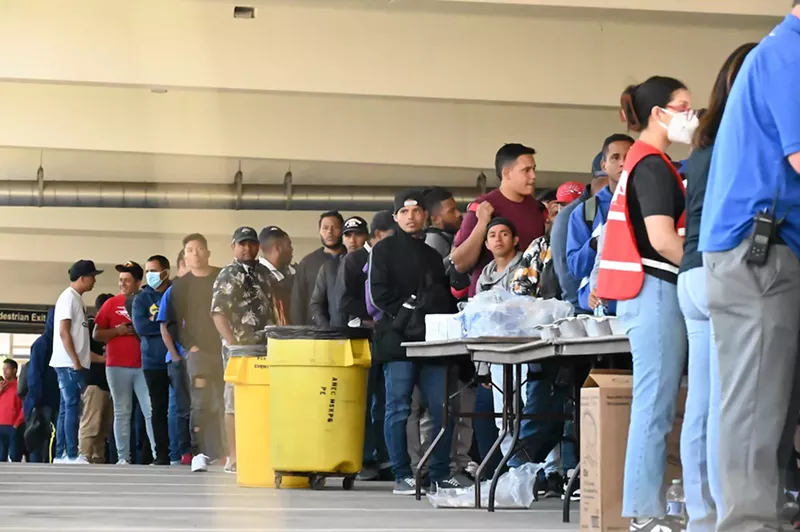 Image: A line of mostly Venezuelan migrants waiting in line for food at the 5th Street Garage on Denver's Auraria Campus.