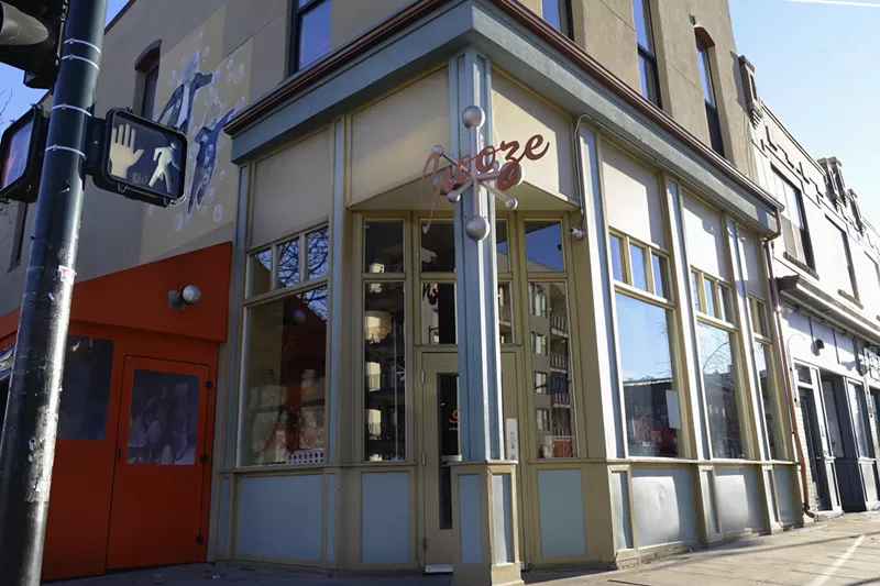 Image: the front entrance of a building with a sign hanging over the top