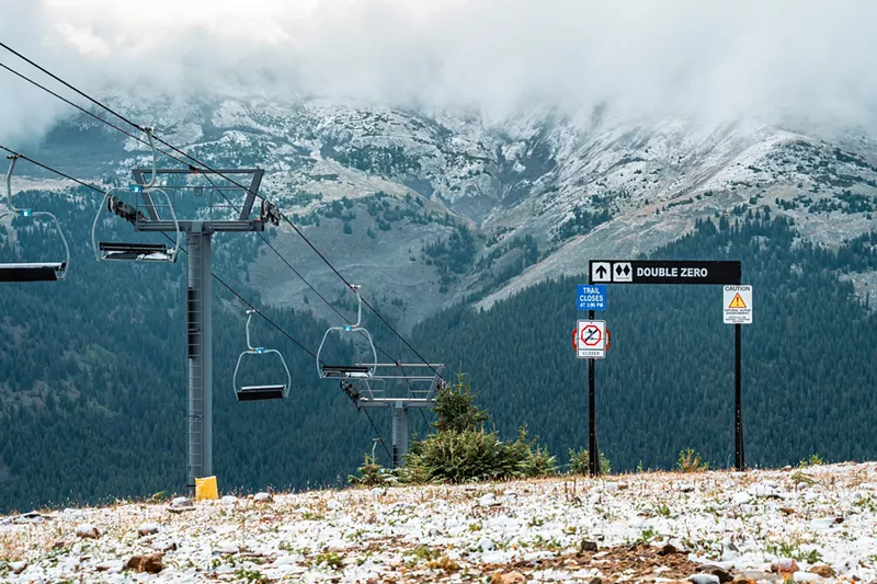 Image: Ski hill with light snow in front of mountain peaks