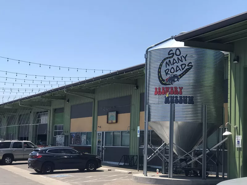 Image: A metal silo with the words "So Many Roads Brewery Museum" in bubble letters on the side.