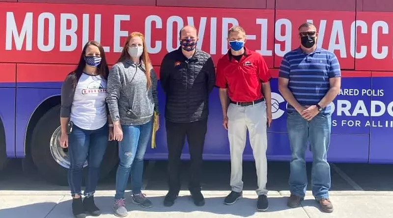 Image: Governor Jared Polis, center, posing with one of the State of Colorado's new mobile vaccine units.