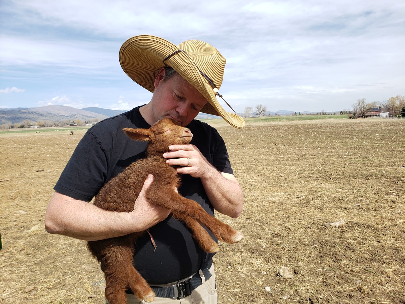 Chef/farmer Eric Skokan cuddles a newborn lamb.