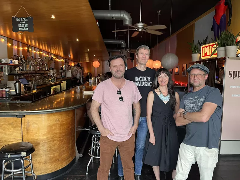 Image: four people posing for a photo inside a bar