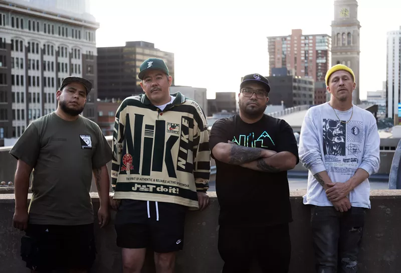 Image: A group of men lean against a balcony.
